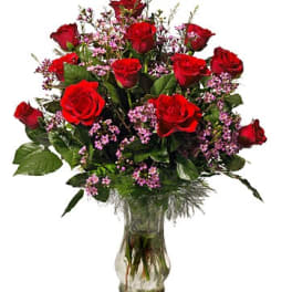 Bouquet of red roses and pink filler flowers in a clear glass vase
