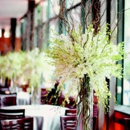 Tall white floral centerpiece in a clear vase with curly branches