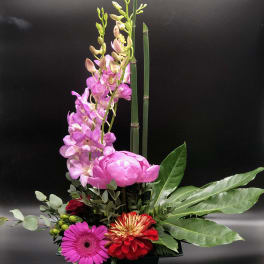 Pink orchids and mixed flowers arranged in a black container
