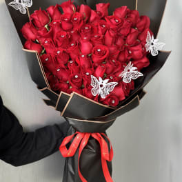 Bouquet of red roses wrapped in black paper with a red ribbon