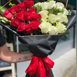 Bouquet of red and white roses wrapped in black paper with a red ribbon