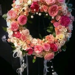 Heart-shaped wreath of pink and white roses with ribbon streamers