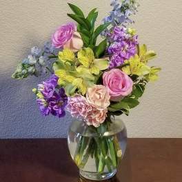 Bouquet of pink, purple, and yellow flowers in a clear glass vase