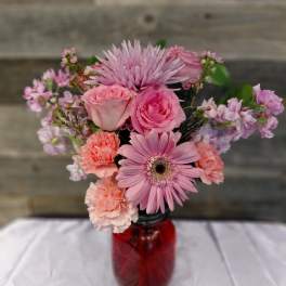 Pink mixed bouquet in a red glass jar vase
