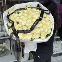 Large bouquet of pale cream roses wrapped in white paper with black ribbon