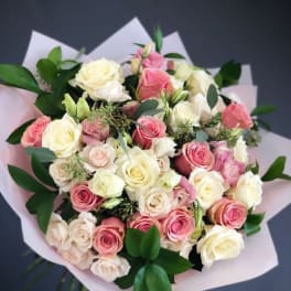 Bouquet of pink and cream roses wrapped in pale paper
