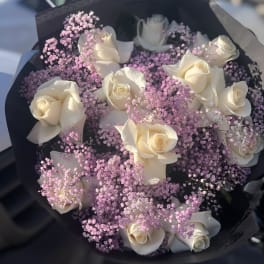 Bouquet of white roses with pink baby's breath in black wrap