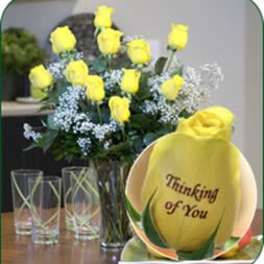 Yellow roses in a glass vase beside a yellow "Thinking of You" gift
