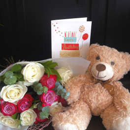 Bouquet of red, pink, and white roses with a teddy bear and birthday card