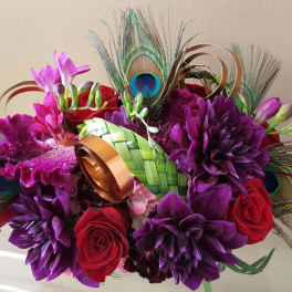 Bouquet of purple and red flowers with peacock feathers and ribbon loops