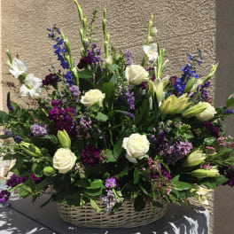 Large basket arrangement of white roses, lilies, and purple flowers