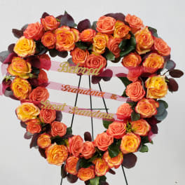 Heart-shaped rose wreath on a stand with pink ribbons