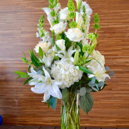 Tall white floral arrangement in a clear glass vase