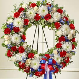 Large red, white, and blue floral wreath on a stand with ribbon