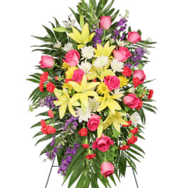 Standing spray of yellow lilies, pink roses, red carnations, and white mums on an easel