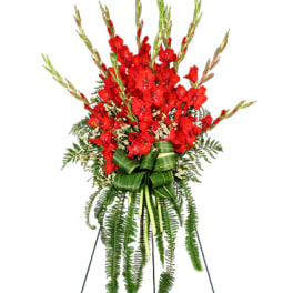 Tall standing spray of red flowers with ferns and a large green leaf bow on a metal easel