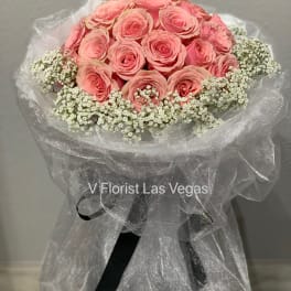 Pink rose bouquet with white baby's breath wrapped in sheer fabric
