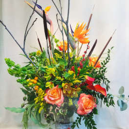 Tall tropical floral arrangement with orange roses and bird of paradise in a vase