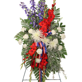 Patriotic standing spray of red, white, and blue flowers on an easel with flag ribbon