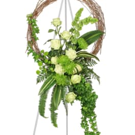 White roses and green flowers arranged on a circular twig stand