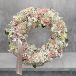 Round floral wreath of pink and white roses with a satin ribbon