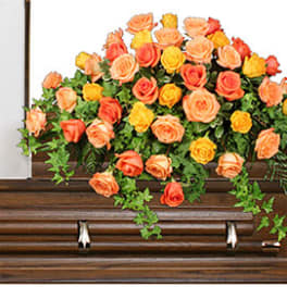 Orange and yellow rose arrangement on a wooden casket
