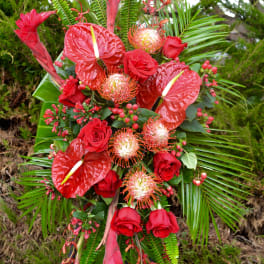 Tall tropical floral spray with red roses and anthuriums on a stand