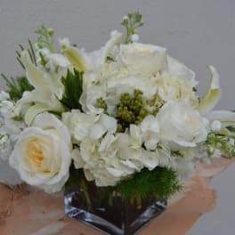 White floral bouquet in a square glass vase with peach wrapping