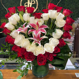 Red and white roses with pink lilies in a glass vase