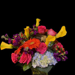 Colorful bouquet with pink roses, yellow calla lilies, and blue hydrangea in a vase