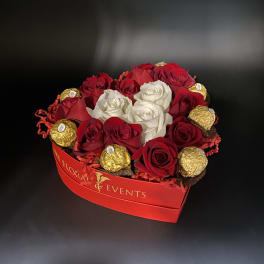 Red and white roses arranged with gold-wrapped chocolates in a red box
