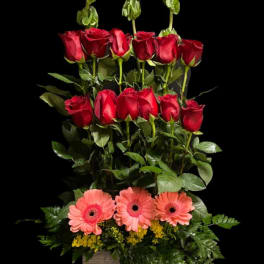 Tall arrangement of red roses and pink gerbera daisies in a square vase