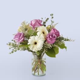 Pink roses and white gerbera daisies in a clear glass vase