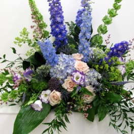 Tall floral arrangement with blue and lavender blooms and pale roses