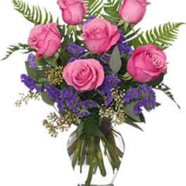 Pink roses arranged in a clear glass vase with purple filler flowers