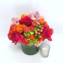 Bright mixed bouquet in a green vase with a small candle beside it