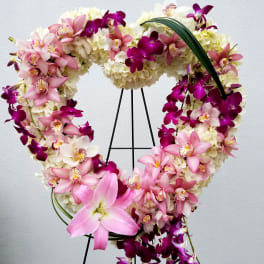 Heart-shaped floral wreath with pink and purple orchids on a stand