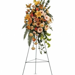 Tall floral standing spray with lilies, roses, and daisies on an easel