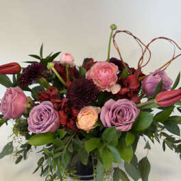 Bouquet of pink and purple flowers with greenery in a black vase