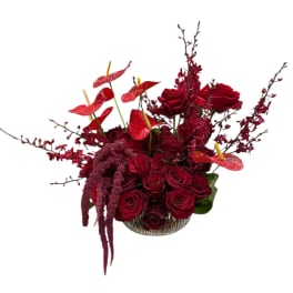 Red rose arrangement in a clear glass bowl with red anthuriums