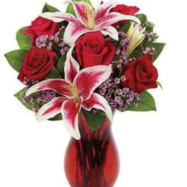 Red roses and pink lilies in a red glass vase