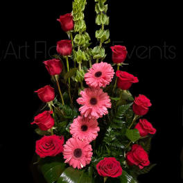 Red roses and pink gerbera daisies in a tall arrangement