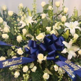 White floral funeral spray with blue ribbons and a central bow