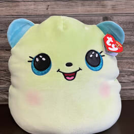 Plush toy with a smiling face and blue ears on a wooden background