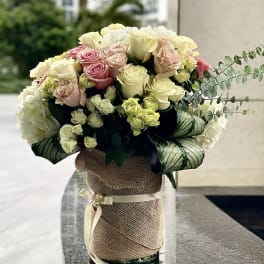 Bouquet of pink and cream roses in a burlap-wrapped vase