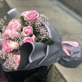 Bouquet of pink roses wrapped in gray paper with a pink ribbon