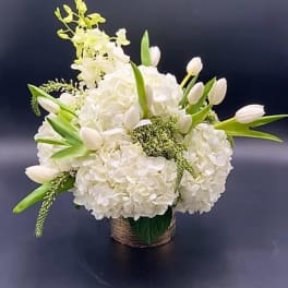 White floral arrangement with tulips and hydrangeas in a woven basket