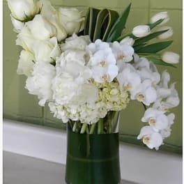 White floral arrangement in a tall green glass vase