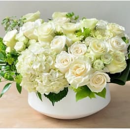 White roses and hydrangeas arranged in a low white bowl