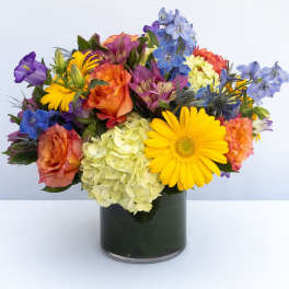 Mixed bouquet of roses, hydrangea, and daisies in a dark glass vase